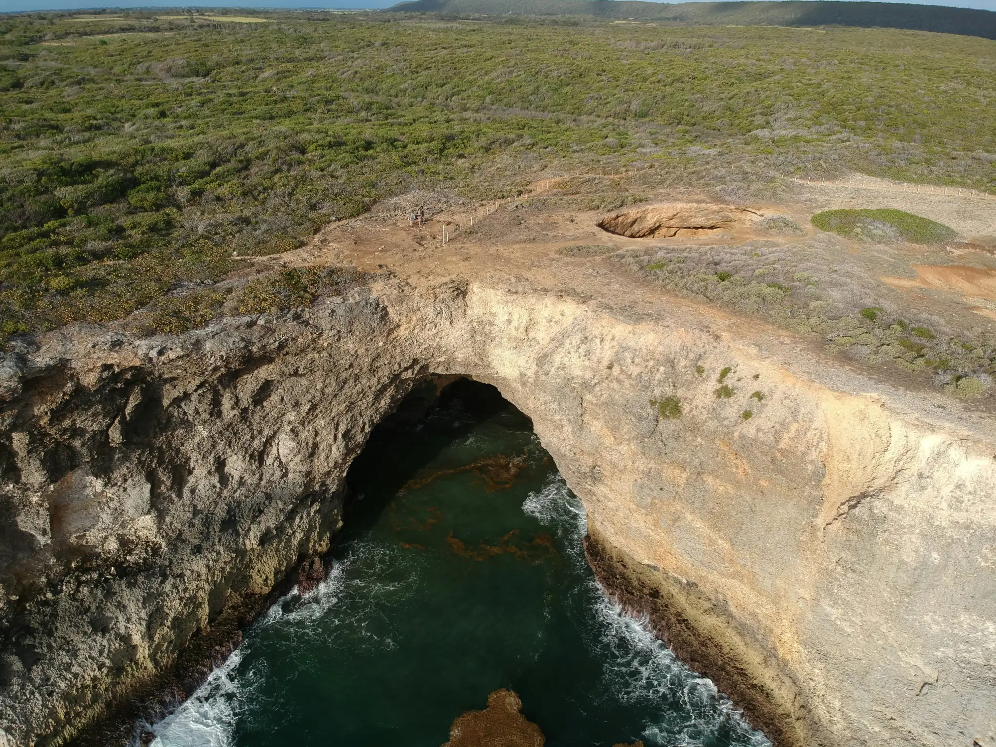 Aerial view of a sea arch in a rocky coastline.