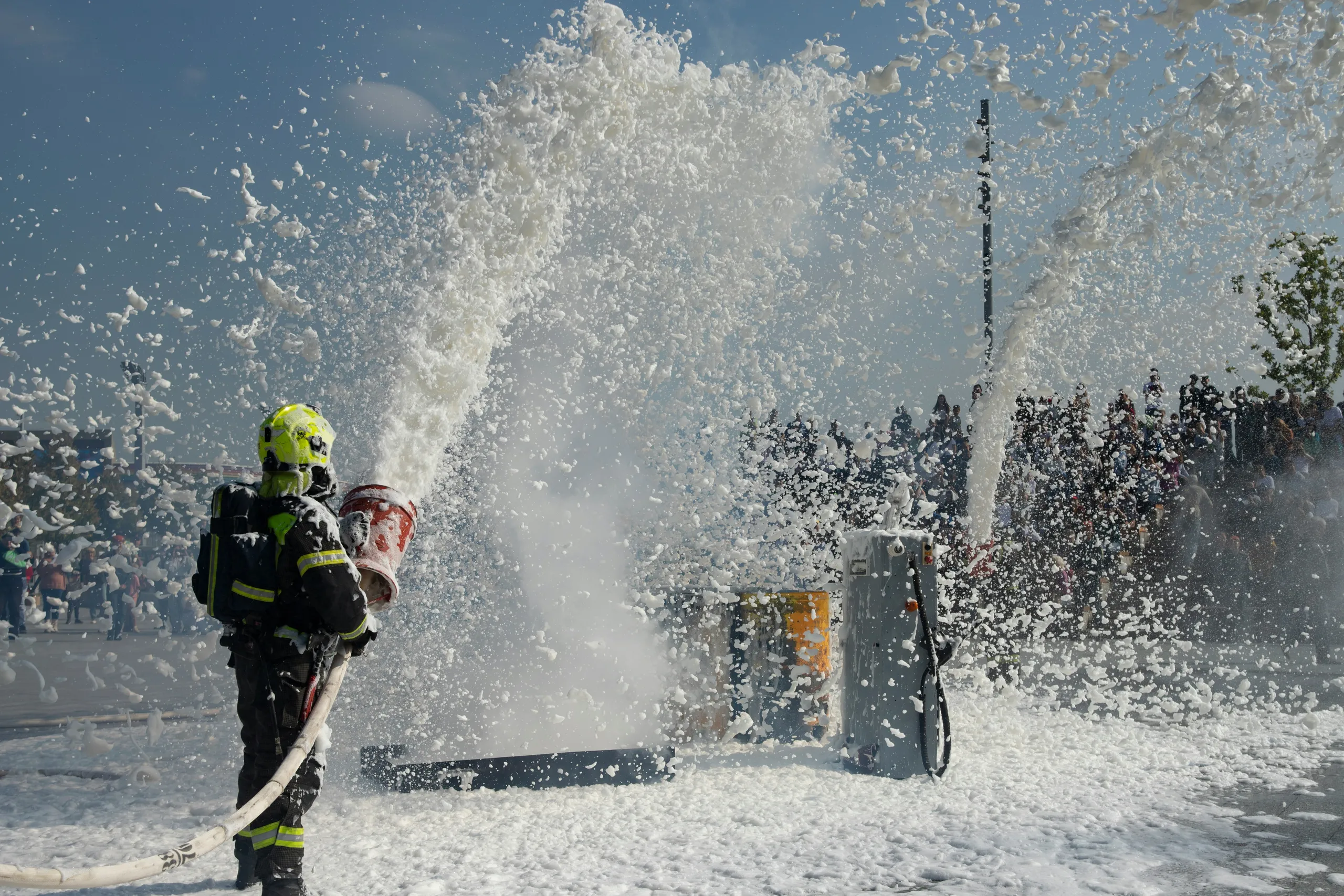A firefighter in protective gear spraying a high-pressure jet of water.