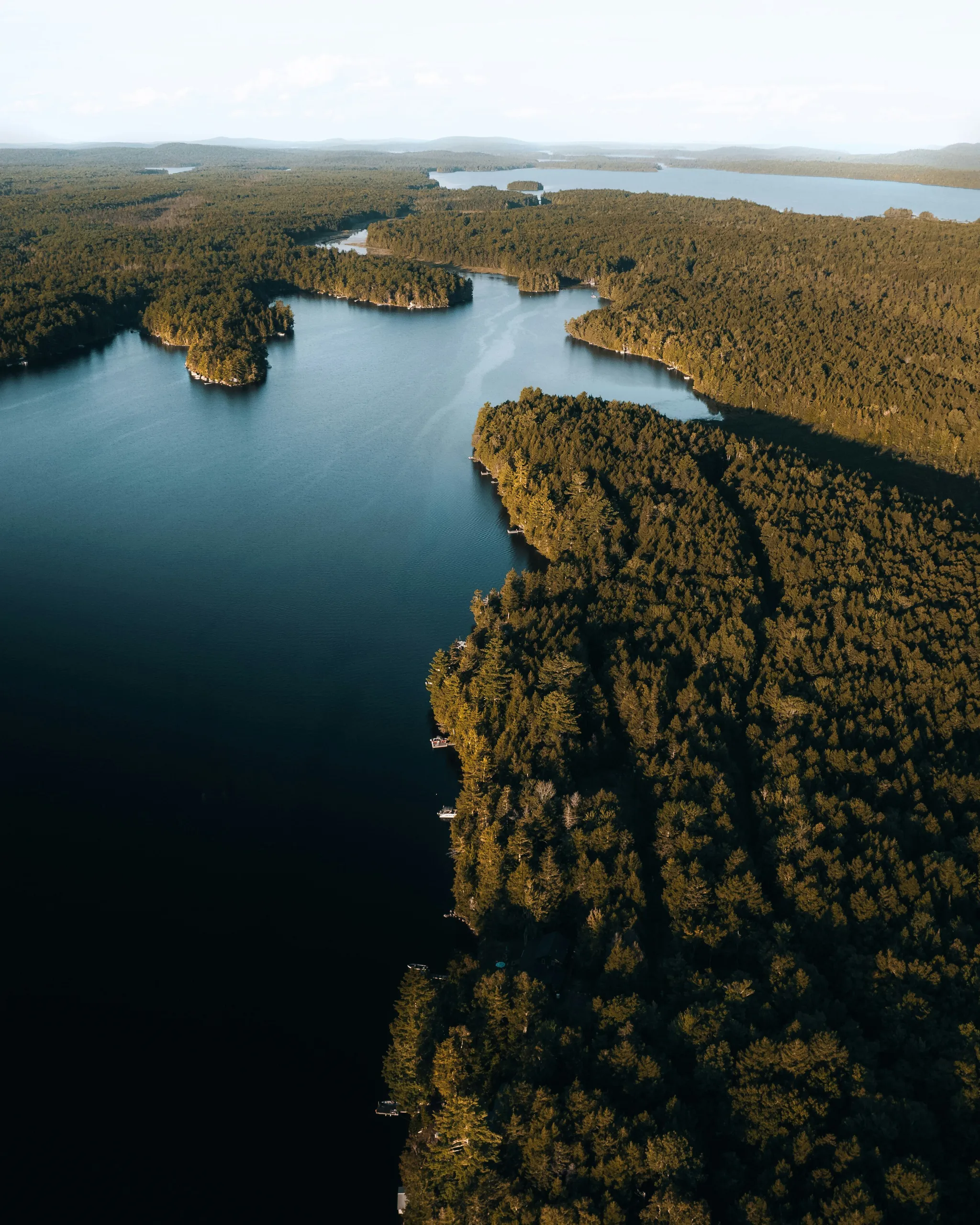 Aerial view of a calm lake between forested shores.