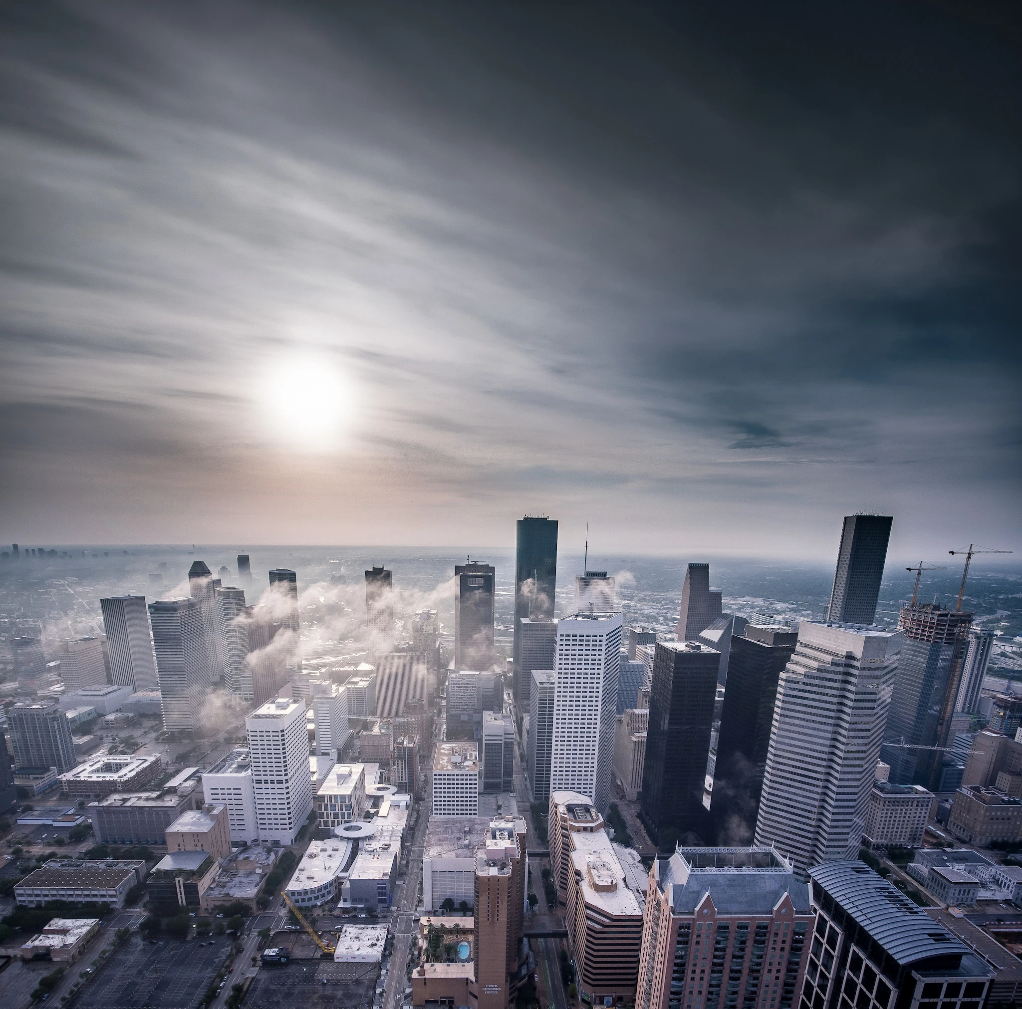 Aerial view of a city skyline with smoke rising between the towers.